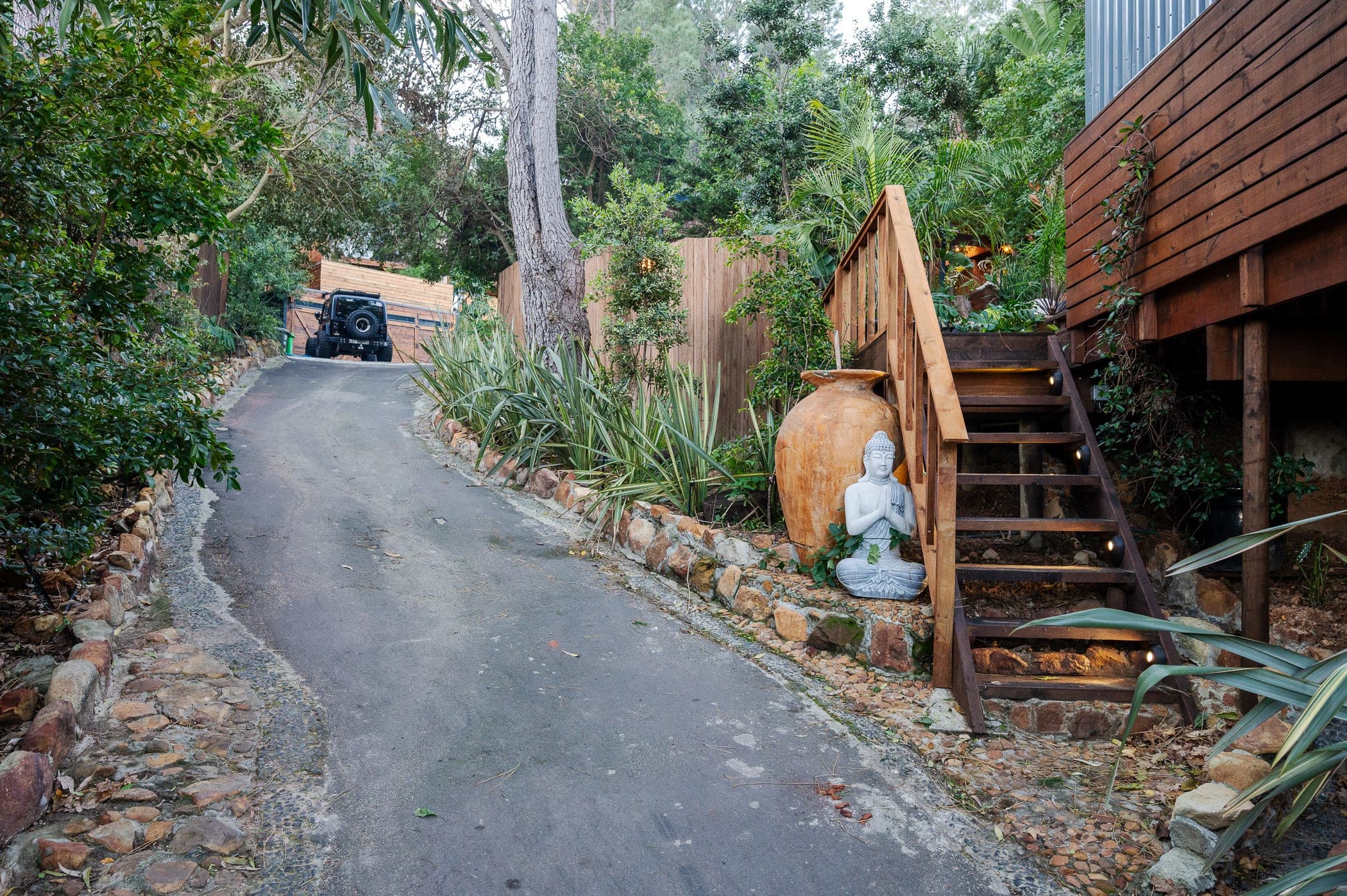 A seated Buddha and clay urn beside the timber steps up to the cabin deck