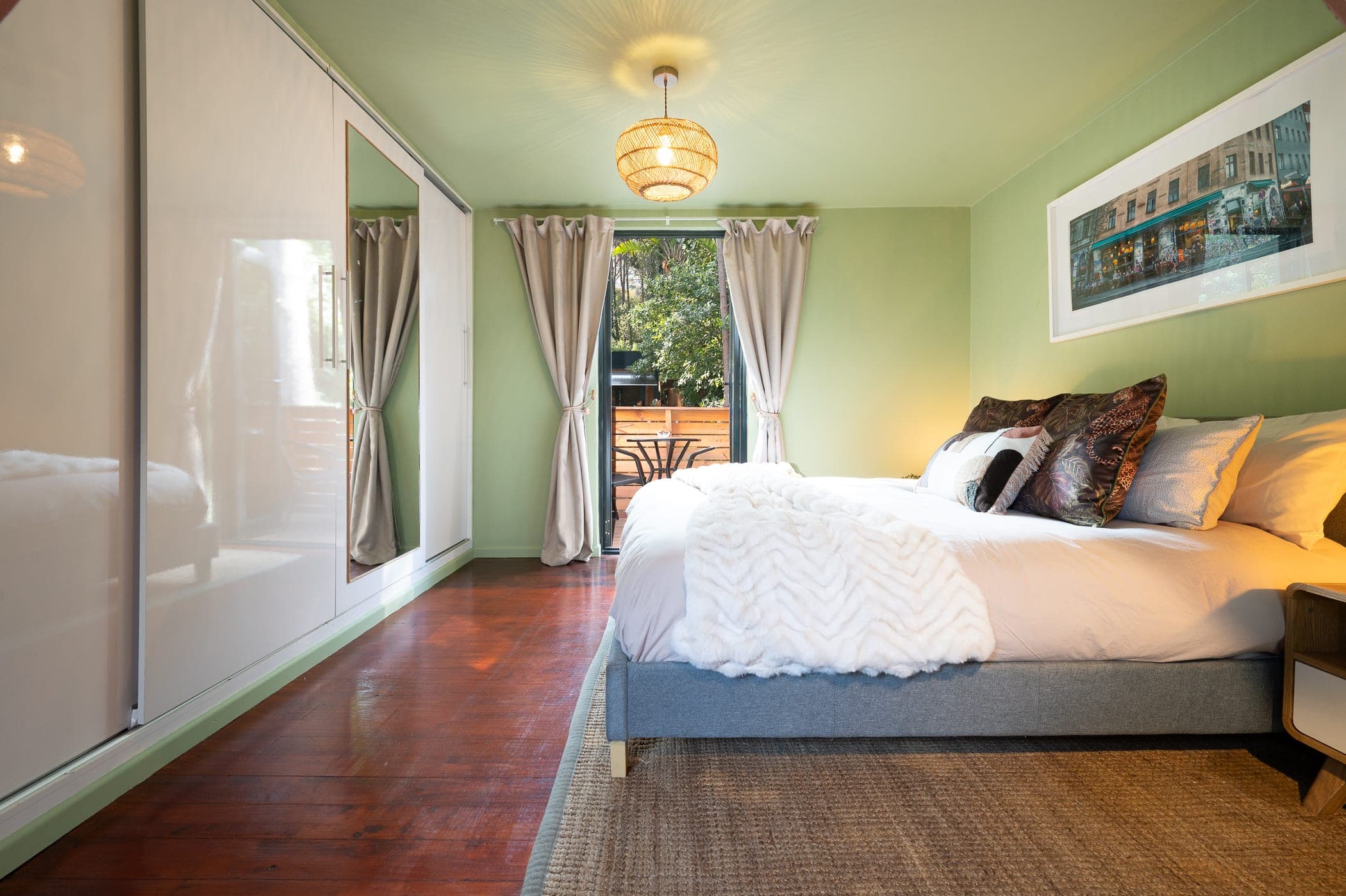 Mirrored sliding wardrobes along the bedroom wall, balcony door curtained beyond