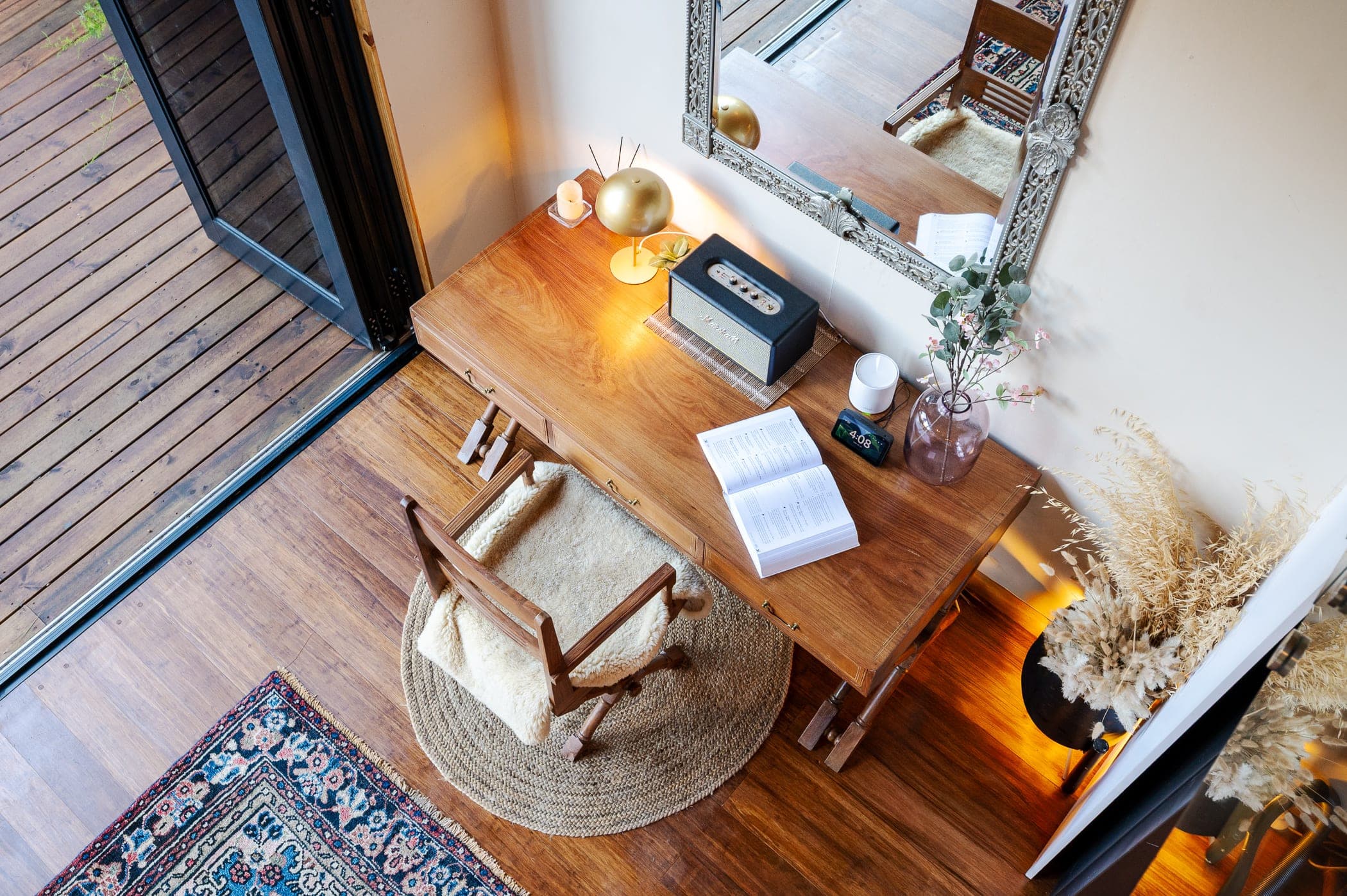 The desk from above, sheepskin chair on a jute rug beside the open door