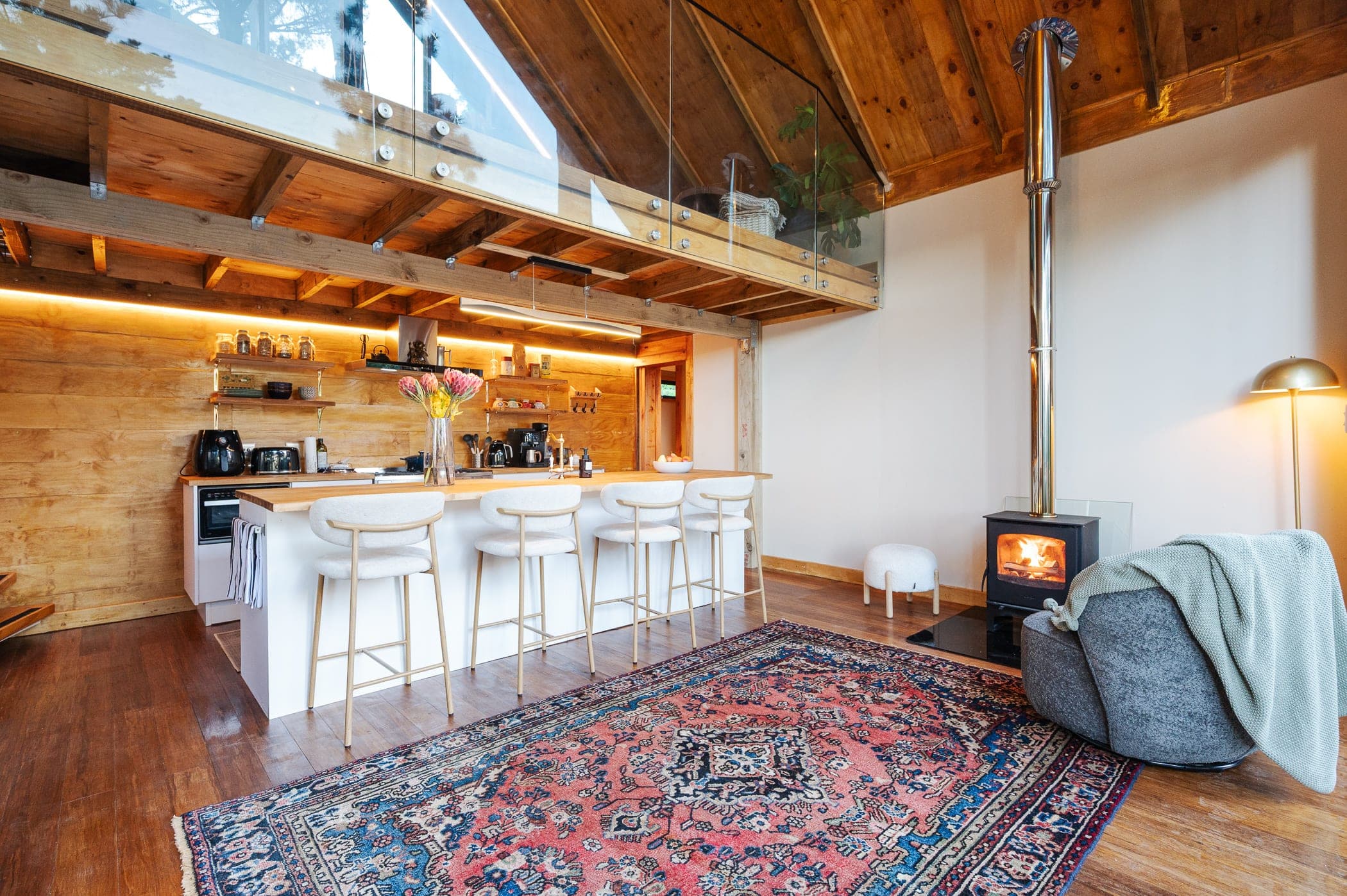 The kitchen island and bar stools under the mezzanine, fire burning alongside