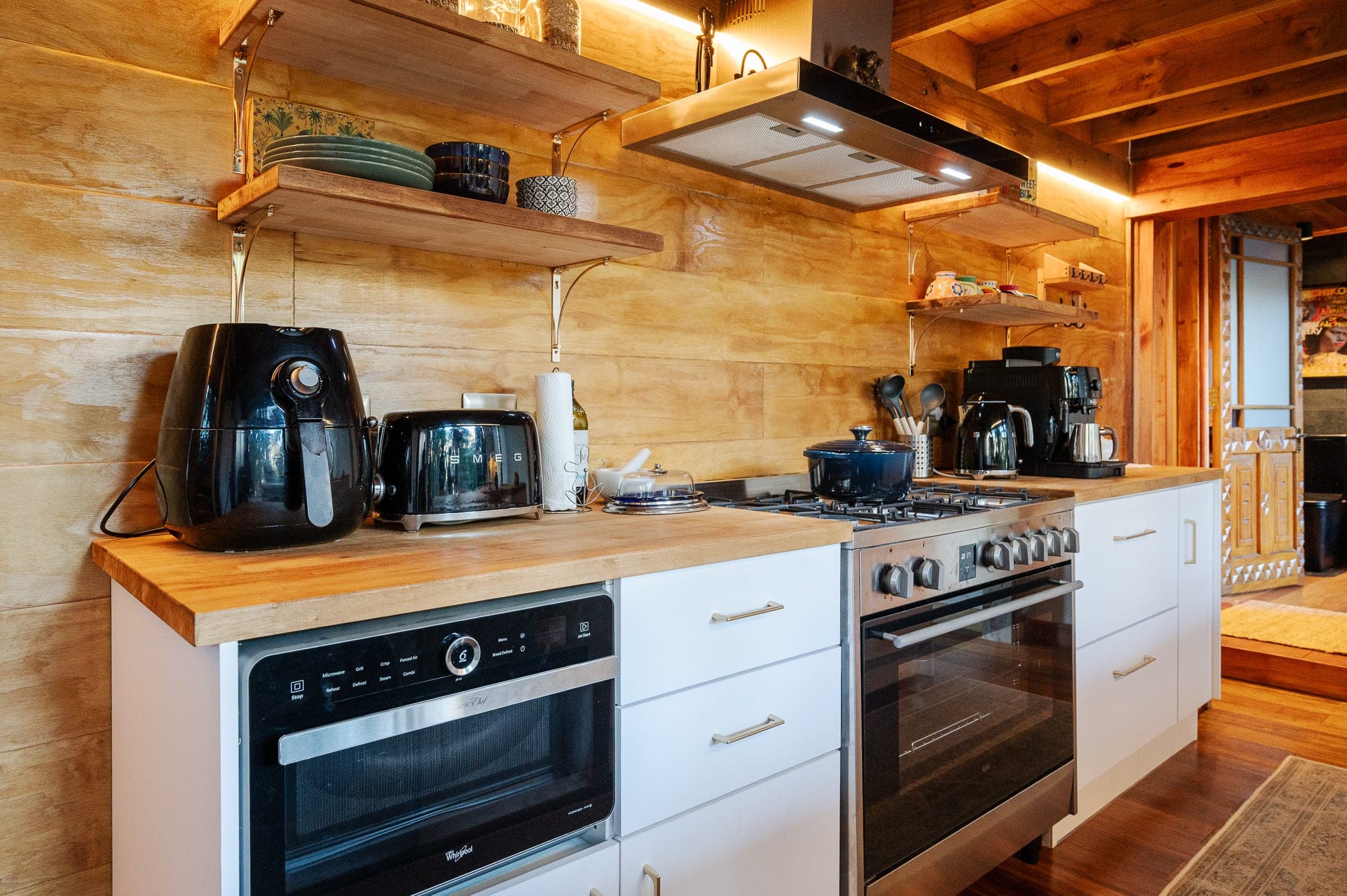 Open shelving above the range, kettle and coffee machine on the timber top