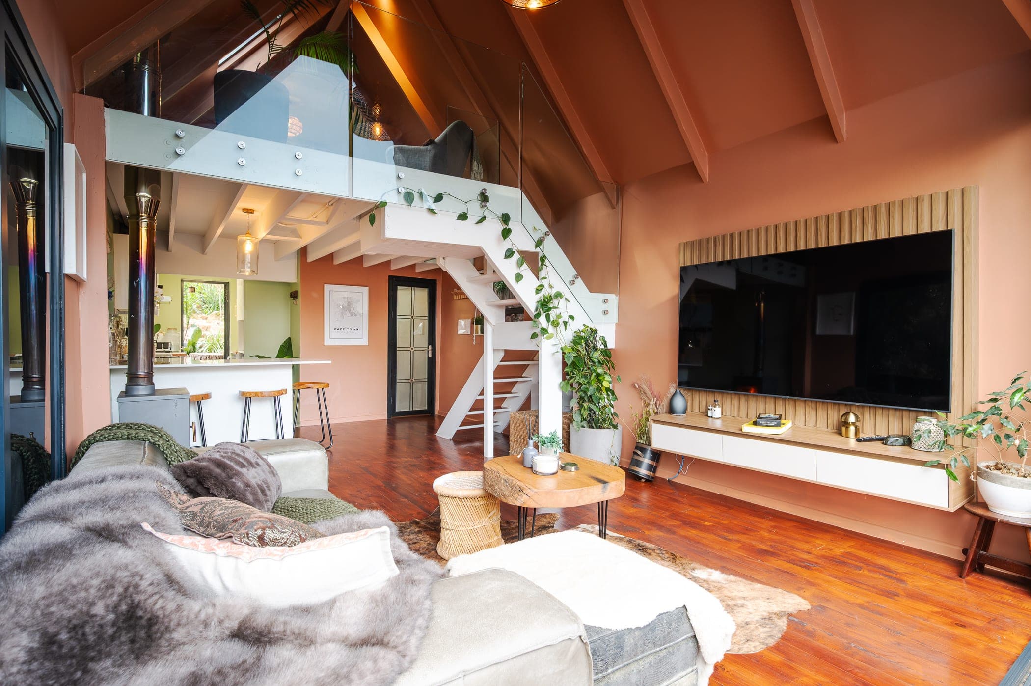 The white staircase climbing to the glass-railed mezzanine, kitchen beyond