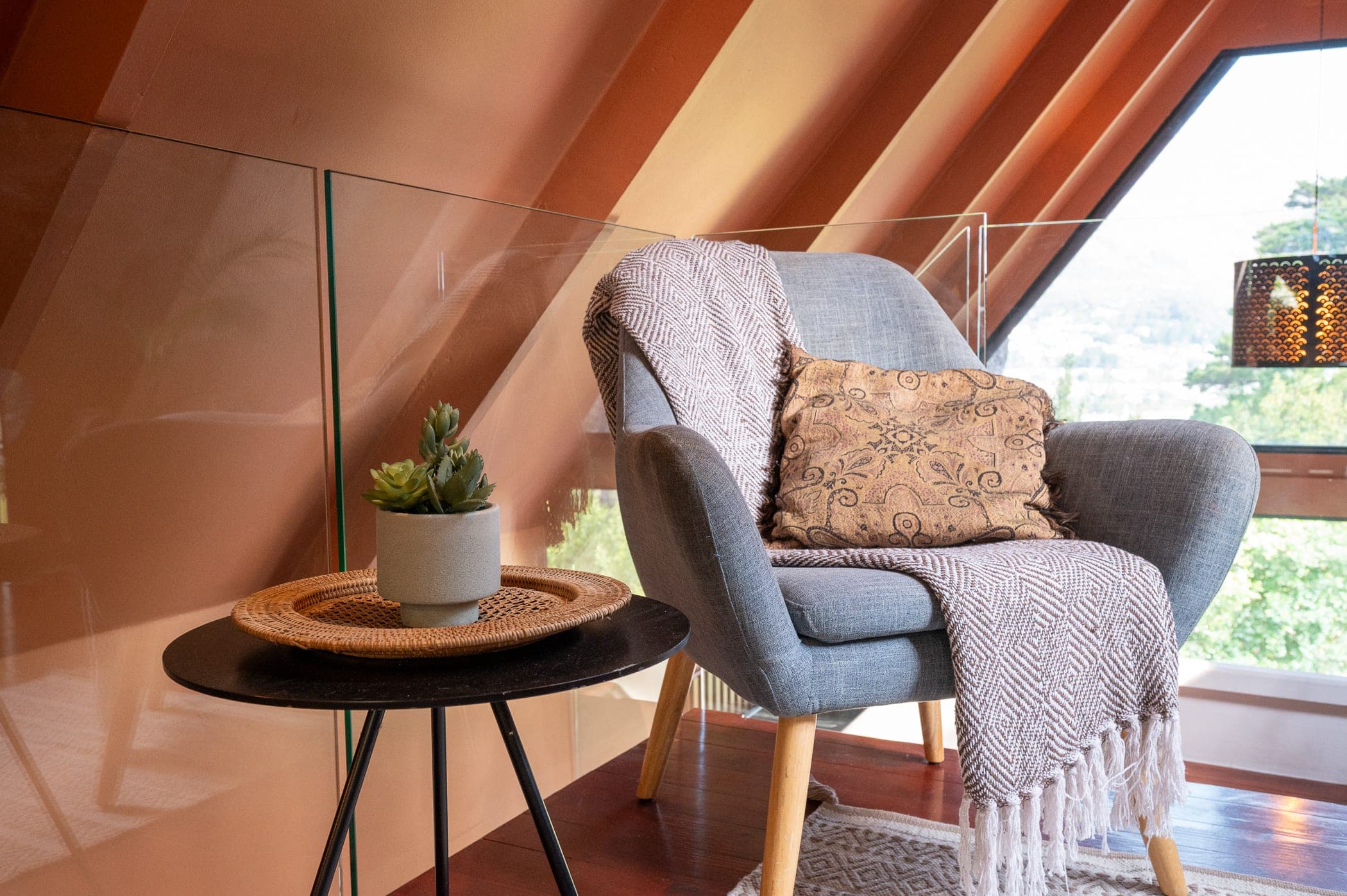 The loft armchair with a woven throw, a succulent on the tripod side table