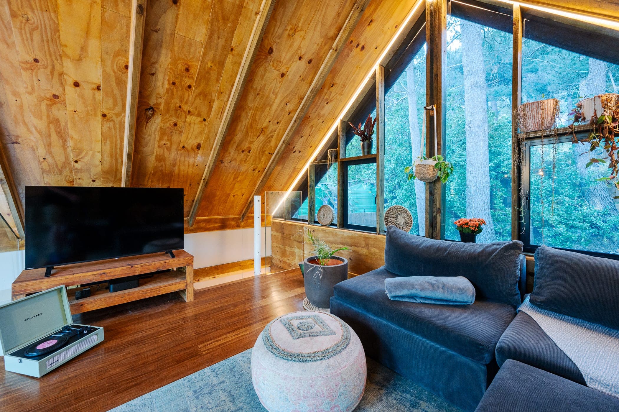A record player and sofa in the loft, forest through the windows