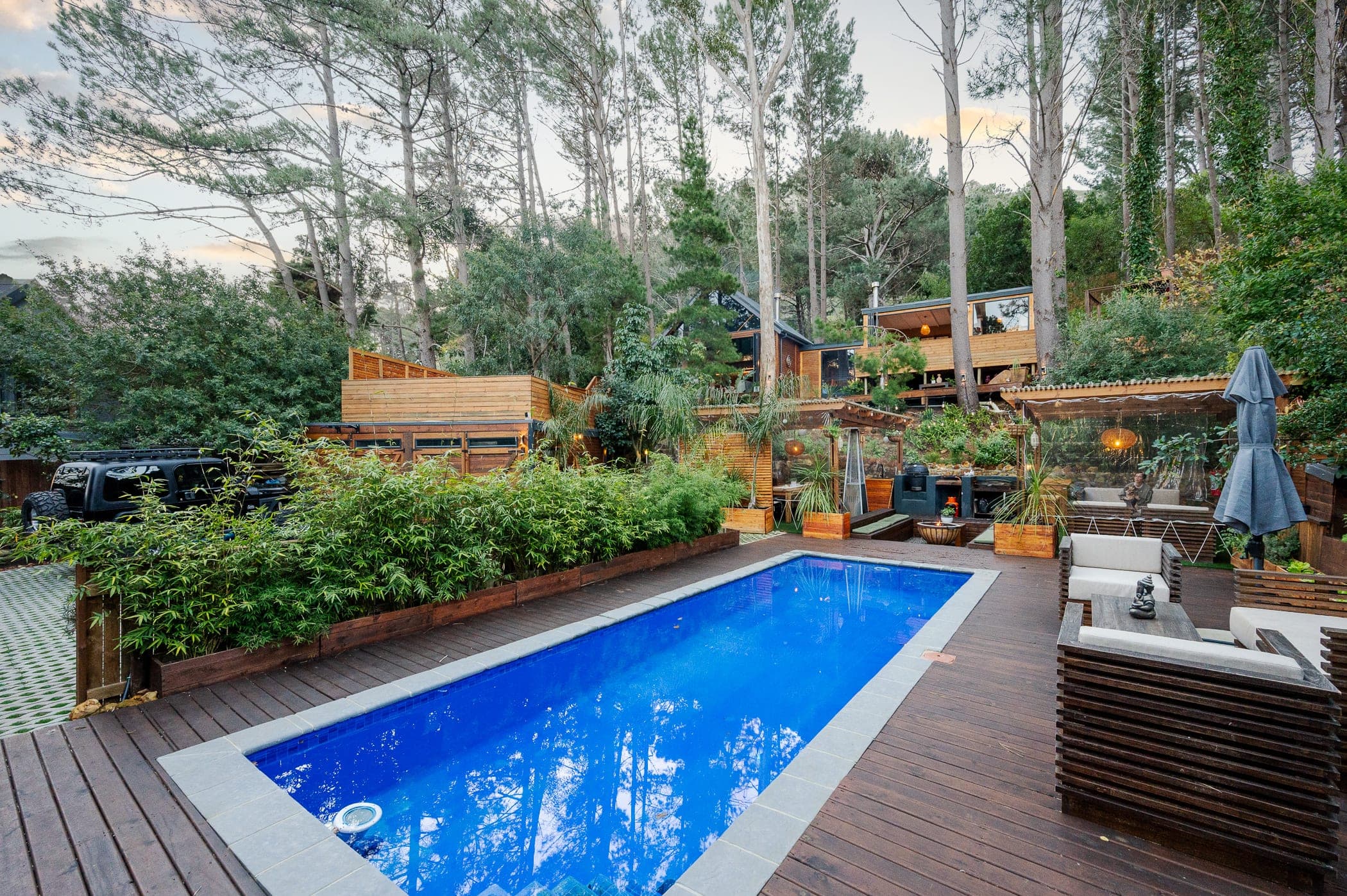 The pool at dusk, a pale sky above the pines and the terraces lit below