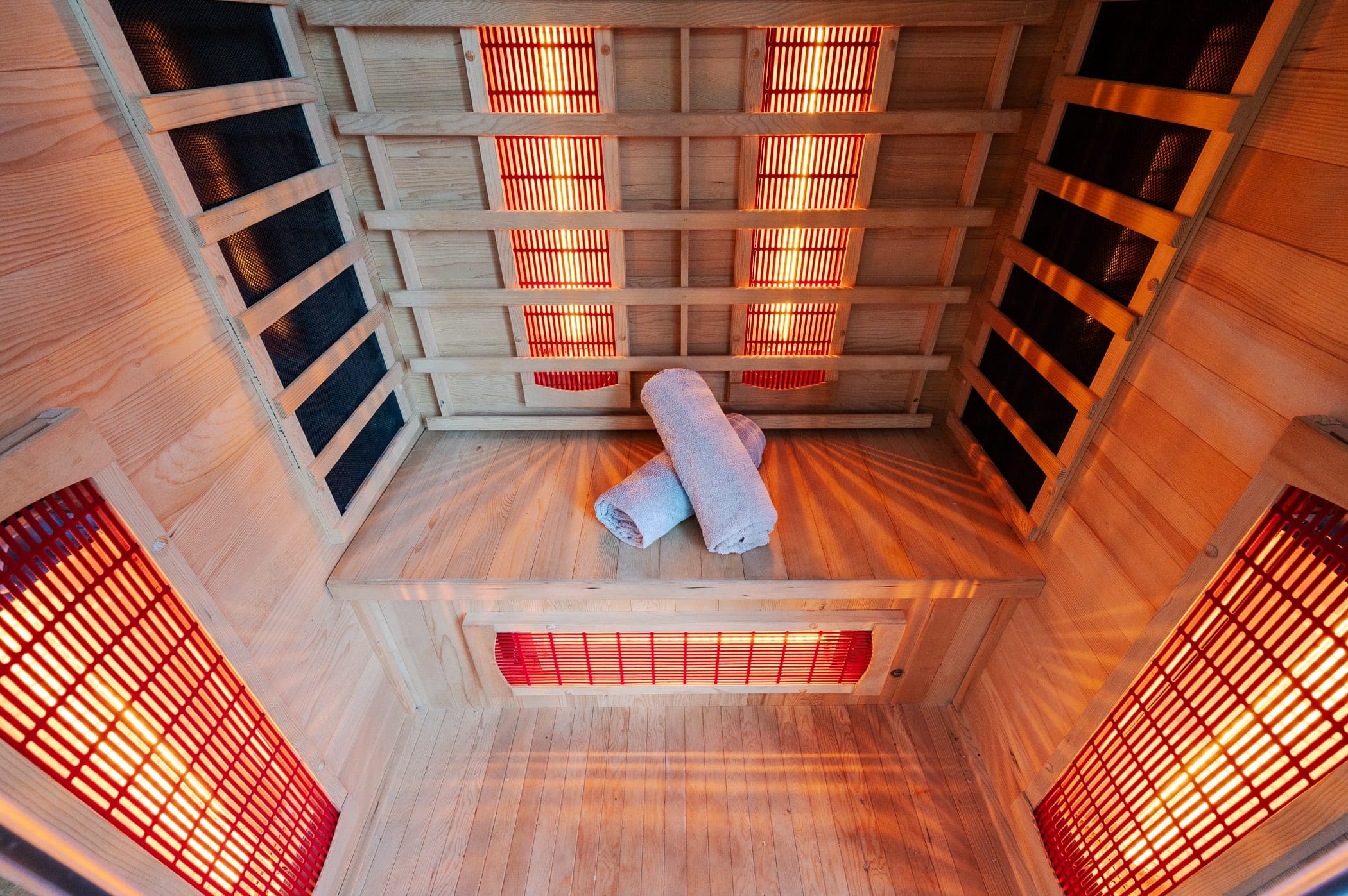 Inside the cedar sauna, infrared panels glowing and towels on the bench