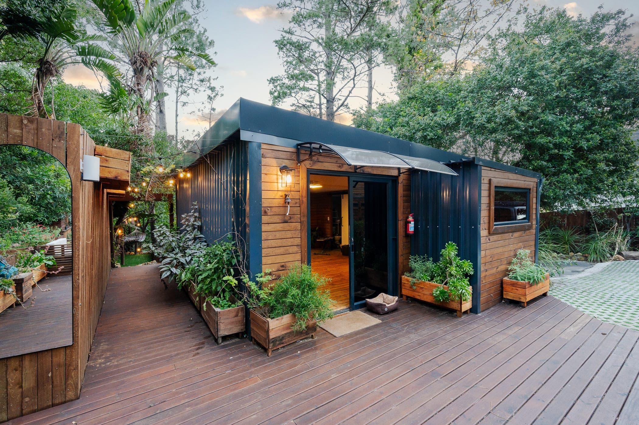 The timber and charcoal studio at dusk, sliding door open to a warm interior